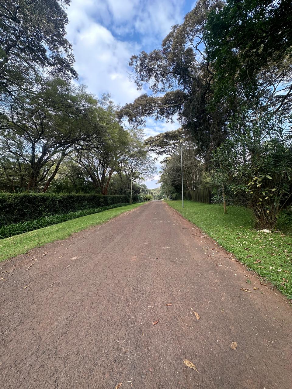 Rich1 Acre Land for Sale in Karen in a gated community, with a driveway and red soil. Asking Price: 70M. Musilli Homes.